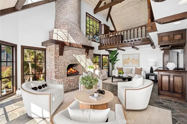 The living room, anchored by an impressive double-height fireplace, opens to an oversized deck that appears to float above the water, while the formal dining room and vintage kitchen with a wet bar for entertaining invite gatherings that linger late into the evening.