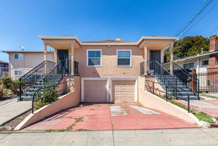 View of front of property with stairs, stucco siding, a chimney, and concrete driveway