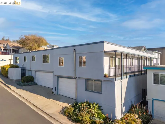 View of front of home with a garage, stucco siding, concrete driveway, and a balcony