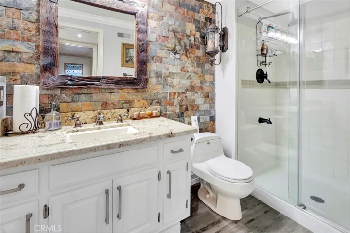 Remodeled main-level bathroom featuring a spacious walk-in shower & glass sliding