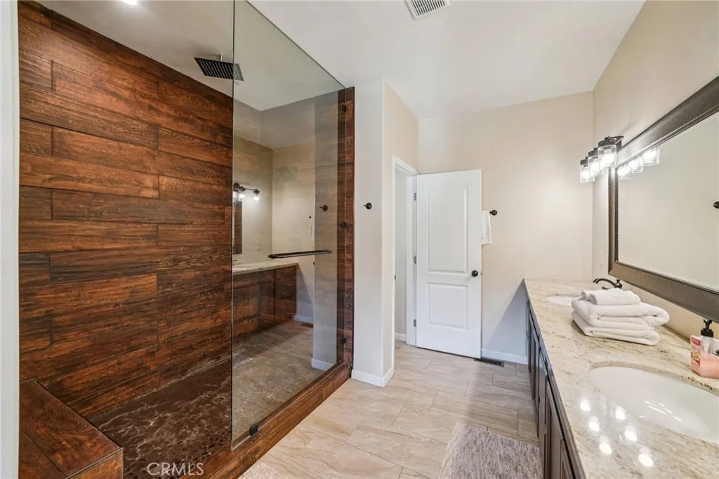 Luxe walk-in shower with wood-look surround and frameless glass enclosure.