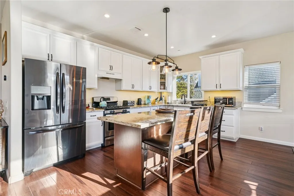 Bright, white Shaker cabinetry, granite counters, and center island with pendant lighting.