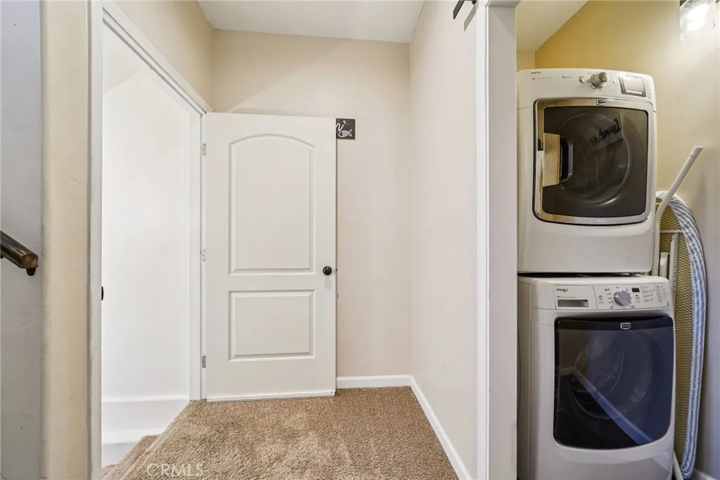 Hallway laundry with stacked washer/dryer and storage niche.