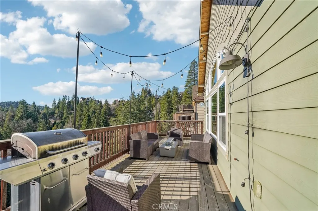 Entertainer’s deck with BBQ, café lights, and sweeping ridge/treetop outlooks.