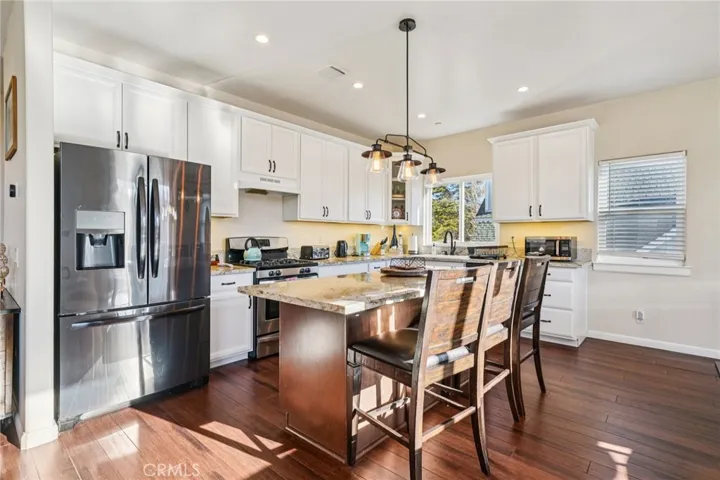 Bright, white Shaker cabinetry, granite counters, and center island with pendant lighting.