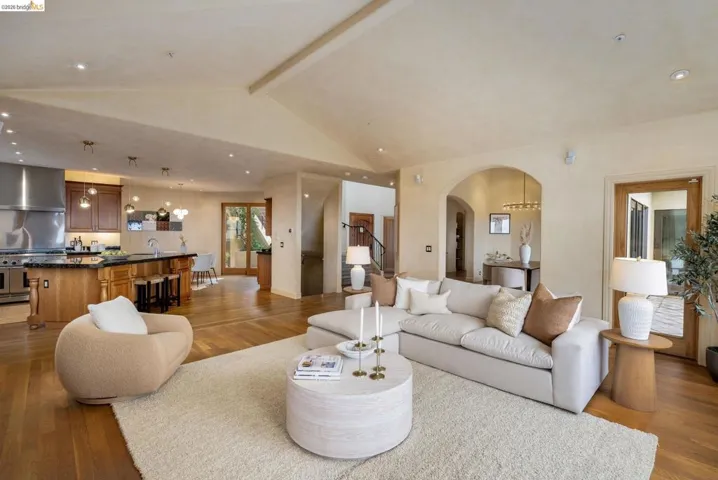 Living room featuring light wood finished floors, recessed lighting, arched walkways, and stairway