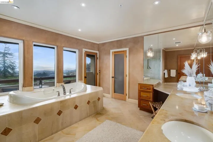 Full bathroom with ornamental molding, a bath, double vanity, and recessed lighting