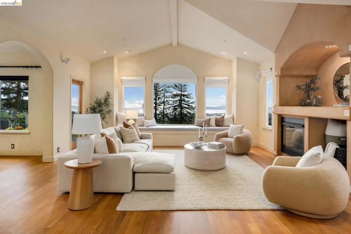 Living room featuring light wood-style floors, a glass covered fireplace, and arched walkways