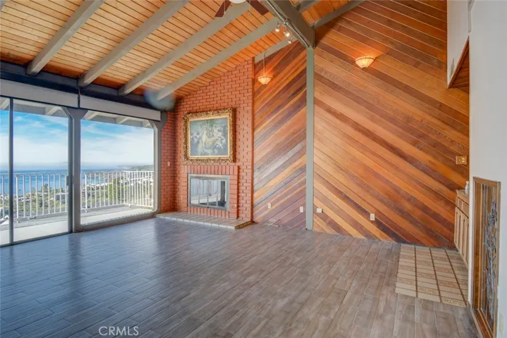 This view is of the living room with high ceilings, a fireplace and views out the large glass windows to Catalina Island and beyond.
