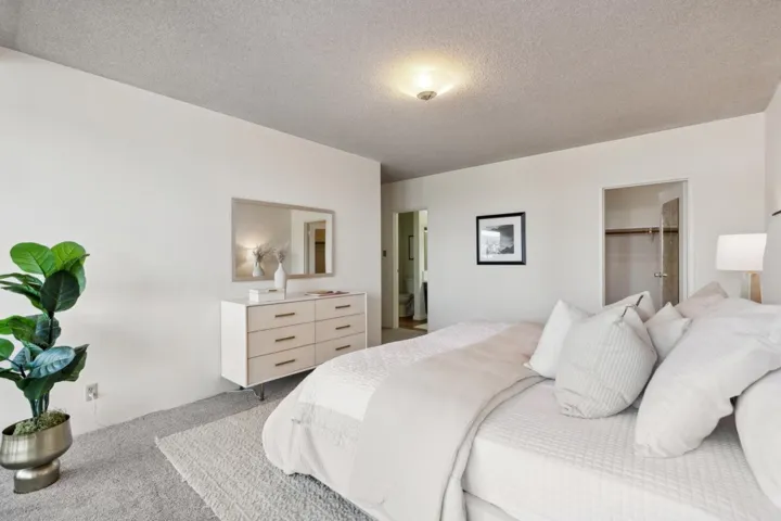 Bedroom featuring a walk in closet, a textured ceiling, and light colored carpet