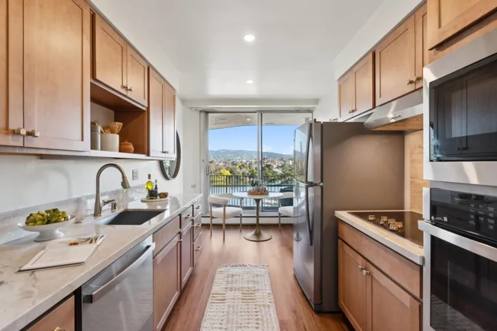 Kitchen with stainless steel appliances, open shelves, dark wood-style flooring, light stone countertops, and under cabinet range hood