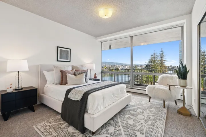 Carpeted bedroom with floor to ceiling windows, a textured ceiling, and a water view