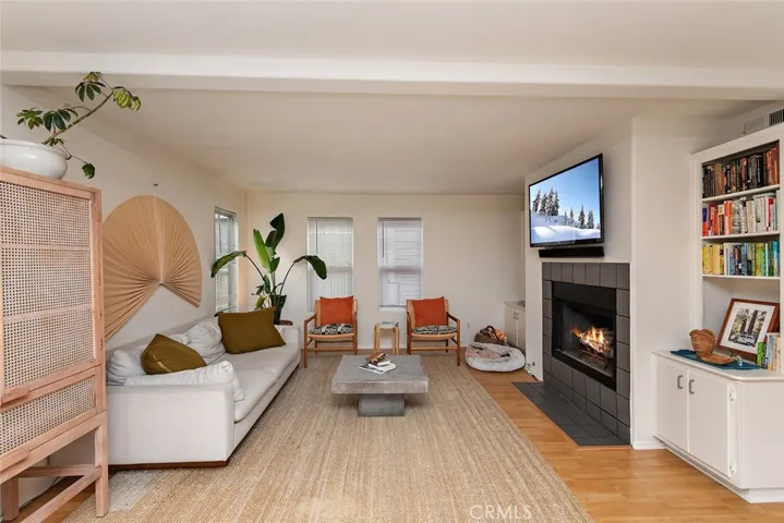 Cozy family room with fireplace, bookshelves and several windows.