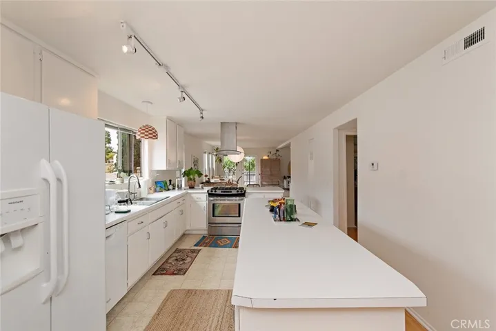 Open kitchen with gas range, dishwasher, refrigerator and stackable washer/dryer