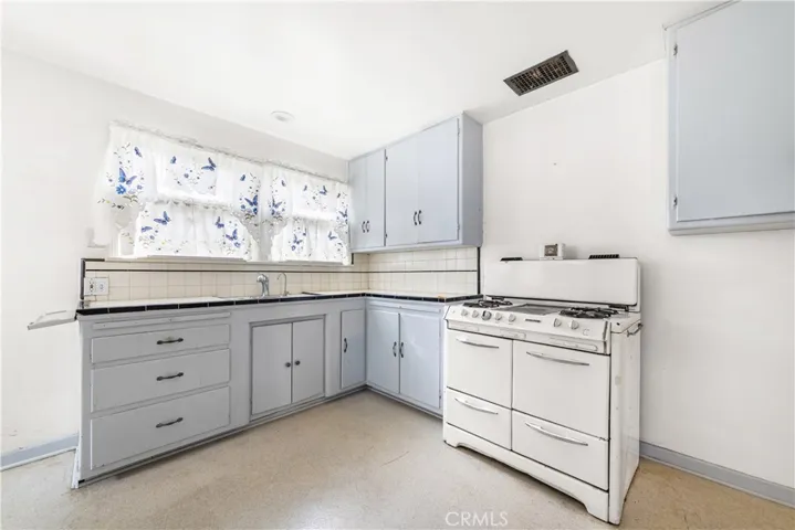 Kitchen sink area with a freestanding gas/oven that will remain with the purchase.