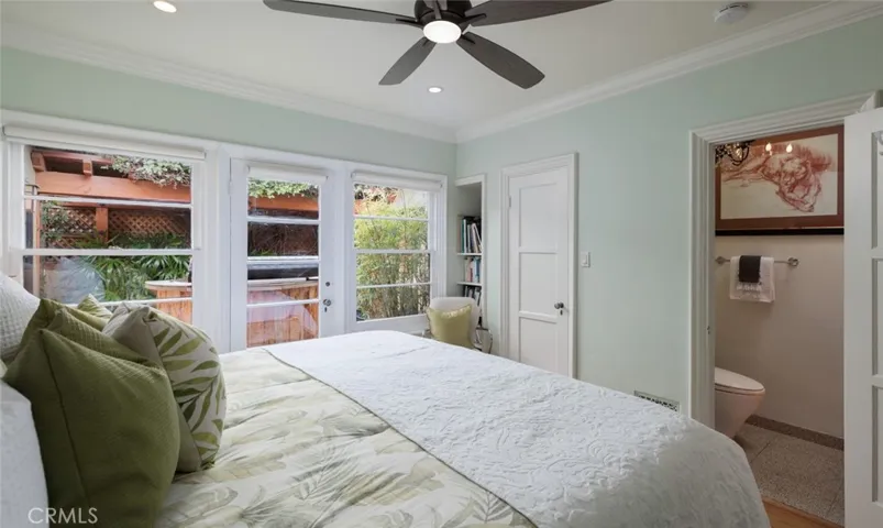 Primary bedroom with attached bath and door to deck with soaking hot tub / spa.
