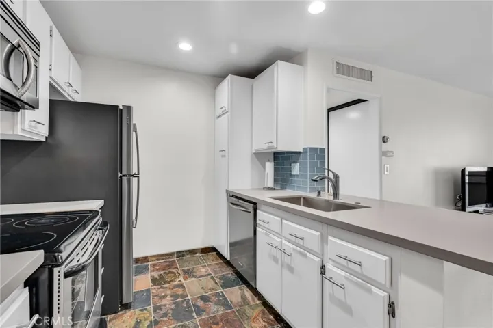 Kitchen with stainless appliances, updated lighting and counters tees