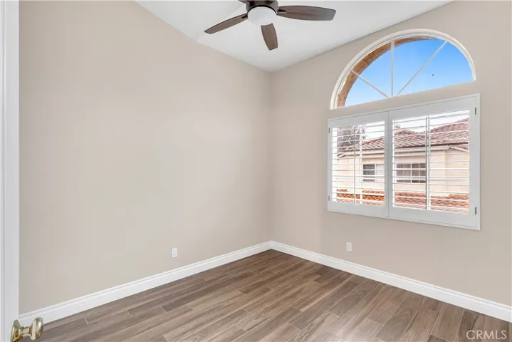 The guest bedroom has a ceiling fan as well as a mirrored closet.