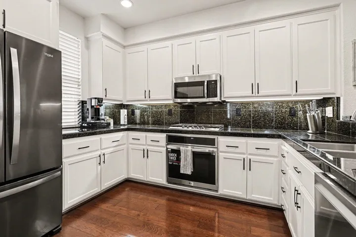 Kitchen featuring appliances with stainless steel finishes, white cabinets, dark wood-style floors, and recessed lighting