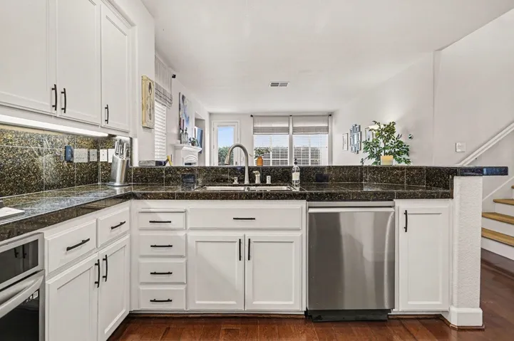 Kitchen with white cabinetry, stainless steel appliances, tile counters, and dark wood-style floors