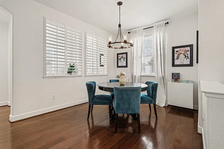 Dining room with dark wood-type flooring, a textured wall, and a chandelier