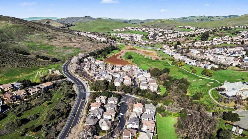 Aerial view of residential area with a mountainous background and a golf course