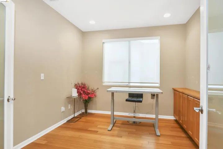 Home office with light wood finished floors and recessed lighting