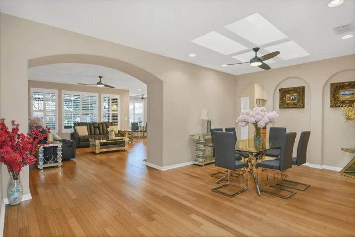 Dining area with ceiling fan, arched walkways, recessed lighting, light wood-style flooring, and a wood stove