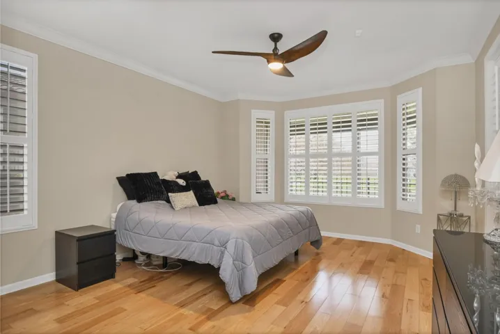 Bedroom with light wood-type flooring, crown molding, and a ceiling fan