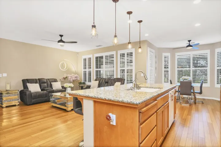 Kitchen featuring ceiling fan, open floor plan, light stone countertops, decorative light fixtures, and recessed lighting