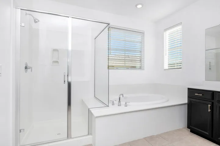 Full bathroom with a stall shower, a bath, vanity, light tile patterned flooring, and recessed lighting