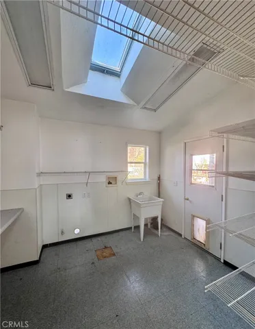 Amazing laundry room with bench for folding, sink and lots of storage a skylight and skylight access to rear deck area.