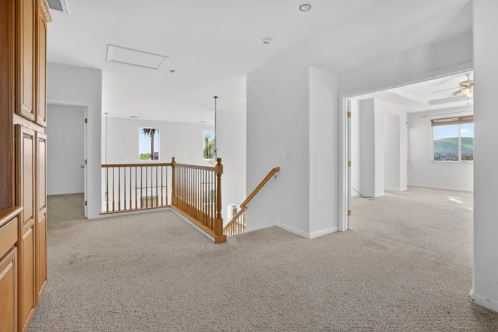 Hall featuring an upstairs landing and light colored carpet