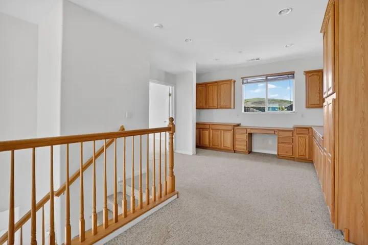 Kitchen with built in desk, light colored carpet, light countertops, brown cabinets, and recessed lighting