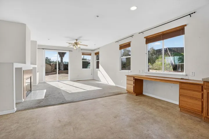 Unfurnished living room with a glass covered fireplace, a desk, ceiling fan, recessed lighting, and light colored carpet