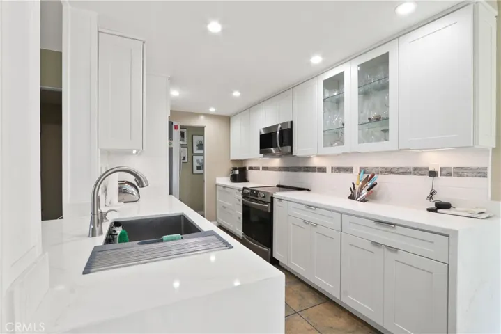 Modern, bright kitchen featuring sleek white cabinetry, stone countertops, and premium under-cabinet lighting