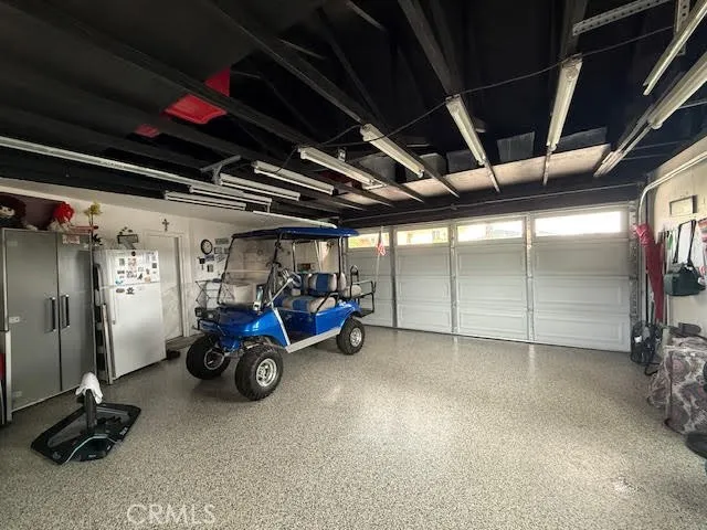 Pull through garage with expoxy flooring, storage rafters, overhead lighting, and tv
