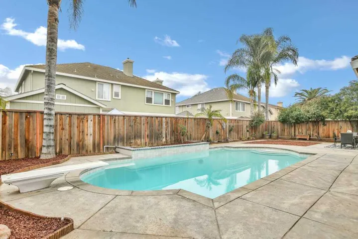View of swimming pool with a fenced backyard, a patio area, and a diving board