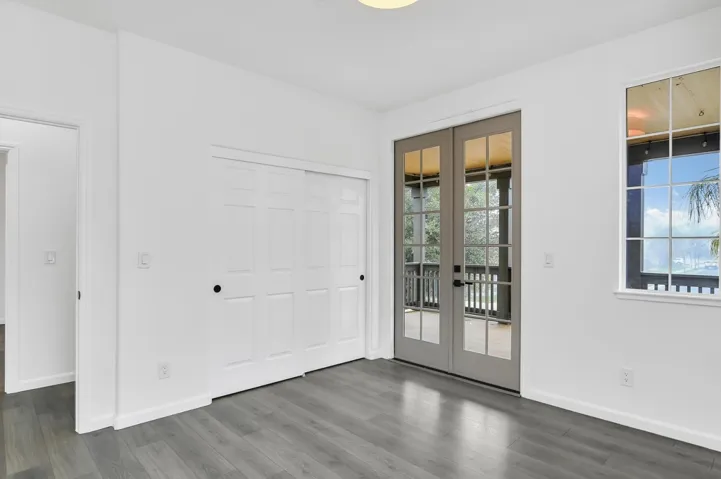 Unfurnished bedroom featuring french doors, a closet, access to outside, and dark wood-type flooring