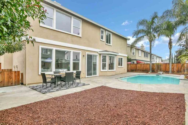 Rear view of house featuring a fenced backyard, stucco siding, a patio, and outdoor dining area