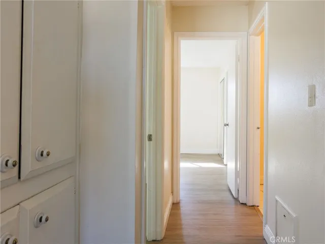 Interior hallway featuring wood-style flooring and built-in storage cabinets for added organization.