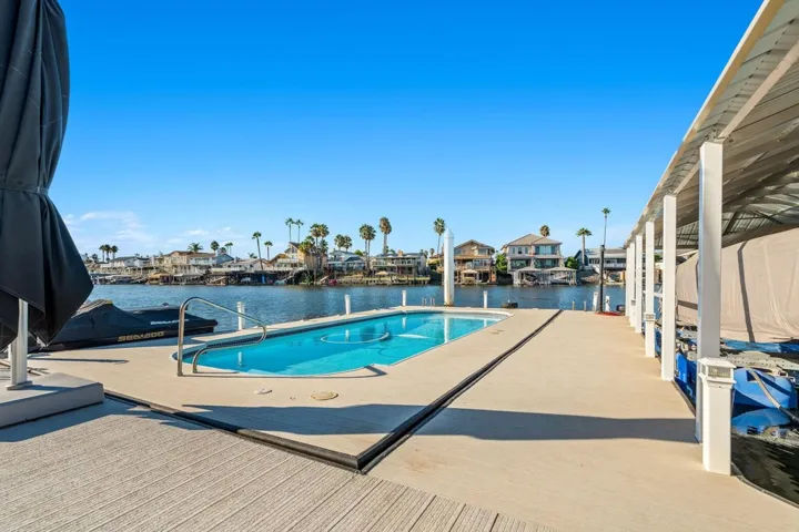 Outdoor pool featuring a water view, a residential view, and a dock