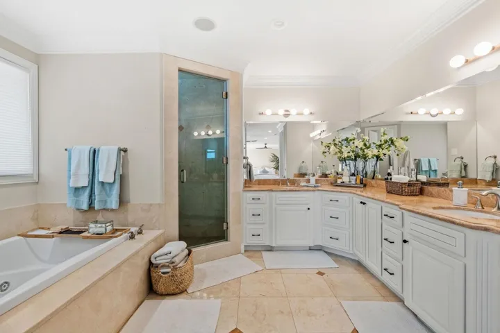 Full bath with double vanity, a bath, crown molding, a shower stall, and light tile patterned floors