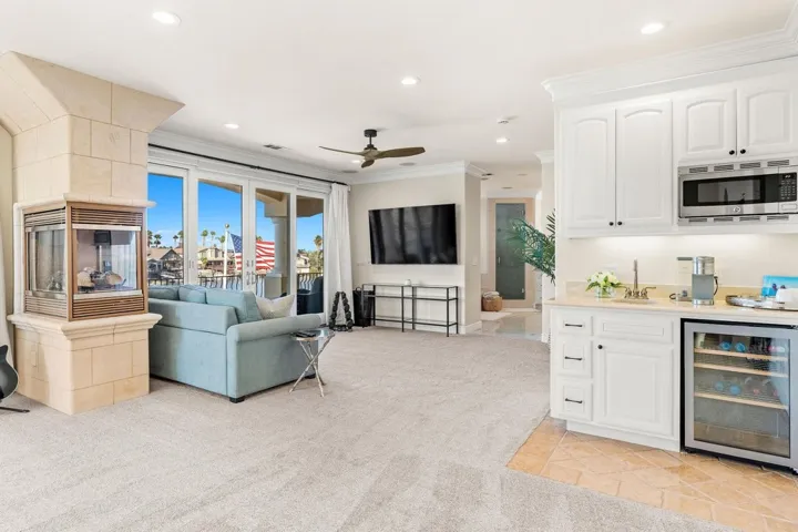 Living area featuring wine cooler, ornamental molding, recessed lighting, a ceiling fan, and light colored carpet