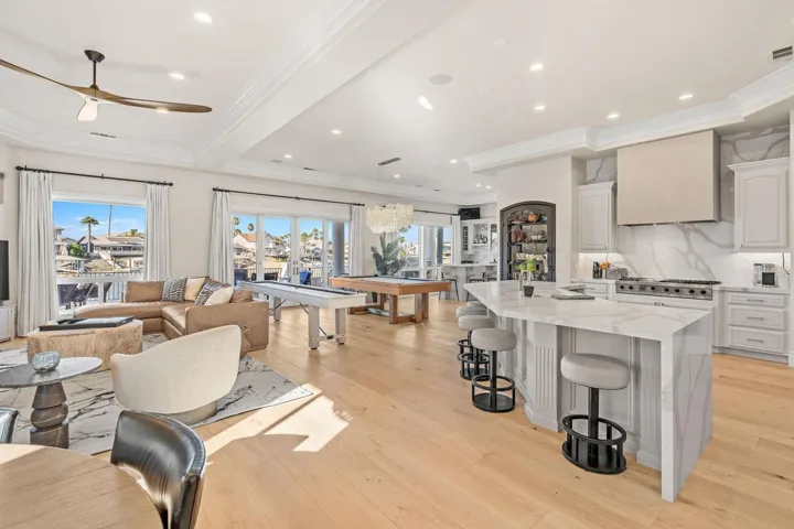 Kitchen featuring pool table, light stone countertops, tasteful backsplash, a kitchen island, and ornamental molding