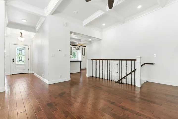 Entrance foyer with coffered ceiling, beamed ceiling, dark wood-style flooring, ornamental molding, and a ceiling fan