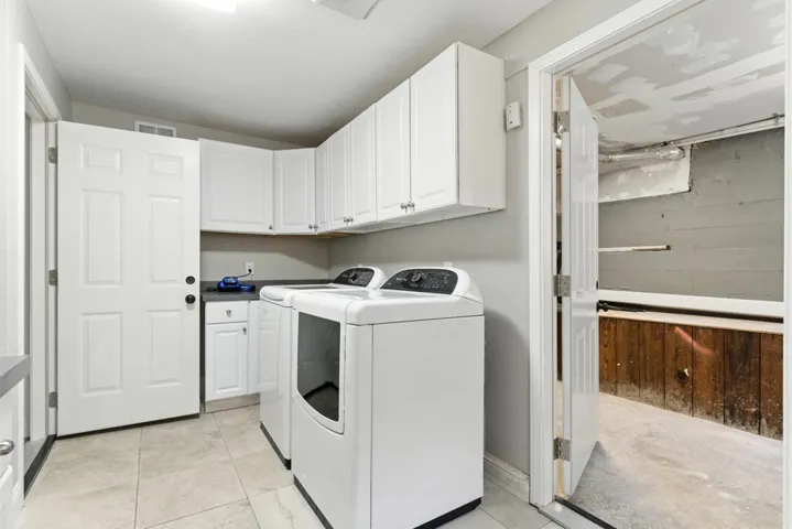Laundry room featuring cabinet space, washing machine and clothes dryer, and light tile patterned floors