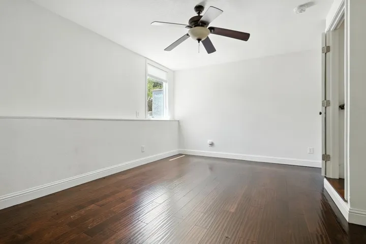 Unfurnished room featuring dark wood-style floors and ceiling fan