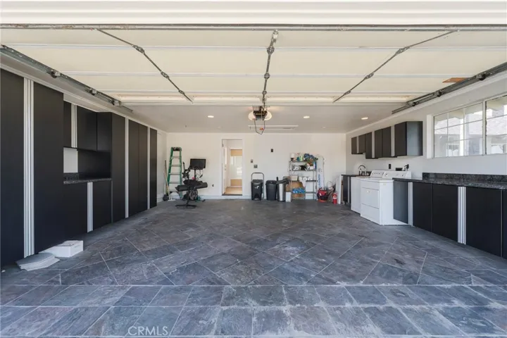 Garage with tile floors, custom cabinets & pull down stairs to storage