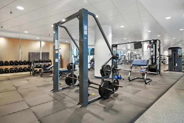 Spacious fitness center with recessed lighting, updated machines and free weights, stretch areas, lap lane pool, reservable mat room, locker rooms with private massage room available by reservation, dry sauna, lockers, and showers.